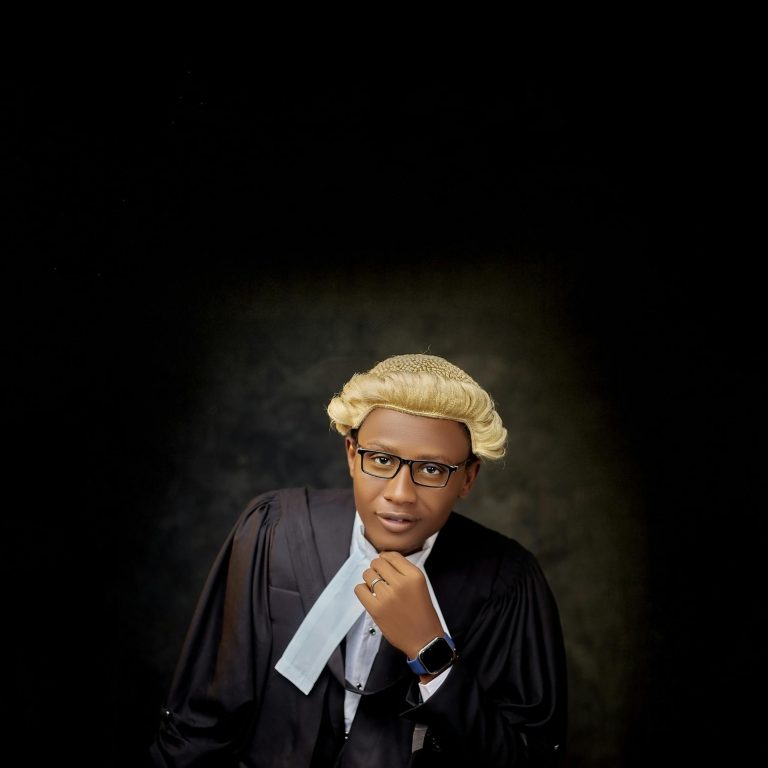 Confident lawyer in traditional attire posing against a dark backdrop.