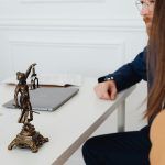 Professional setting with lawyers and Lady Justice statue discussing legal documents.